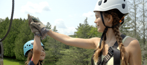 Two girls high-five on a zipline platform