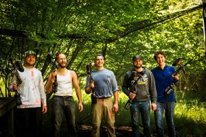 a group of 5 men poses for a photo during a round of paintball in wisconsin
