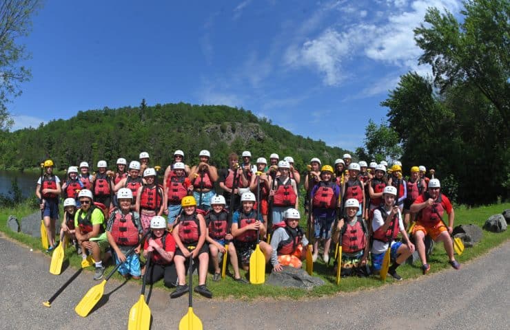 a group of 25 youth poses before whitewater rafting on the Menominee River with Wildman Resort