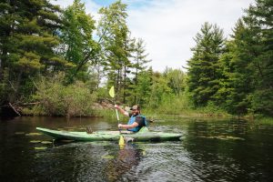 a man paddles through lily pads on a kayak tour in Crivitz