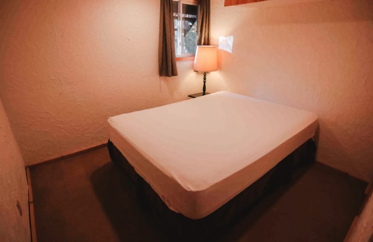 image of Peshtigo Lodge private bedroom with bed, side table and lamp