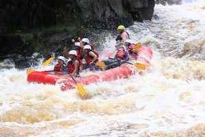 a group of rafters, guided by Wildman Adventure Resort staff, powers through rapids on the Menominee River