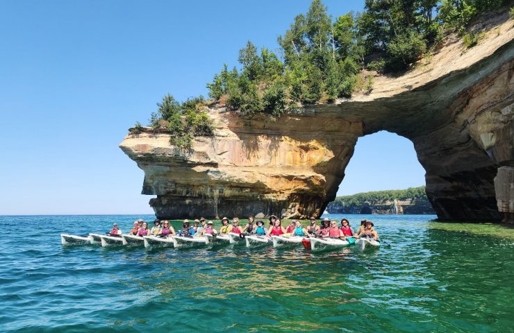 a group of sea kayakers poses below the arch at Lover's Leap at Pictured Rocks